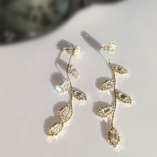 Load image into Gallery viewer, Image shows Diana Dangle Earrings on a white background in direct sunlight with a pair of sunglasses behind them.