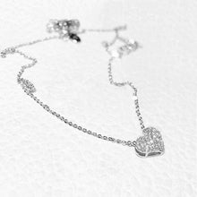 Load image into Gallery viewer, Image shows silver-finish Elizabeth Heart Necklace resting on model's fingers.