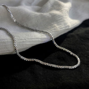 Image shows Arianwyn Chain lying on black and white fabrics.