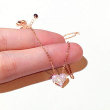 Load image into Gallery viewer, Image shows rose gold-finish Elizabeth Heart Necklace resting on model&#39;s fingers.
