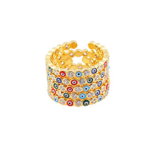 Load image into Gallery viewer, Image shows five gold-tone Colourful Jackie Evil Eye rings stacked on each other on a flat surface.
