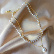 Load image into Gallery viewer, Image shows gold-tone Princess Pearl Necklace laid on pink satin fabric surface.
